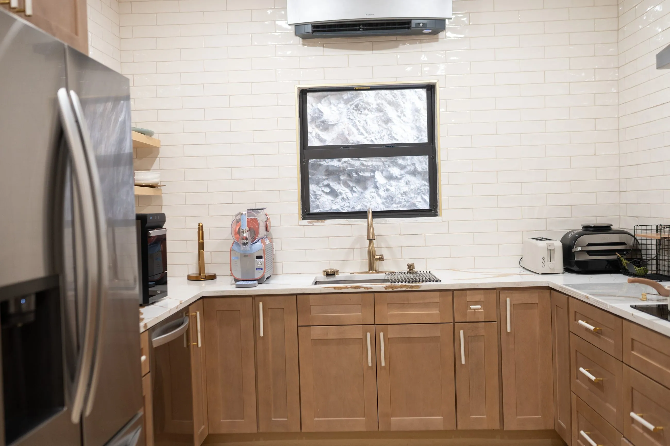Full kitchen with marble worktops, white subway tile, wood cabinetry, wall ovens and a French-door refrigerator