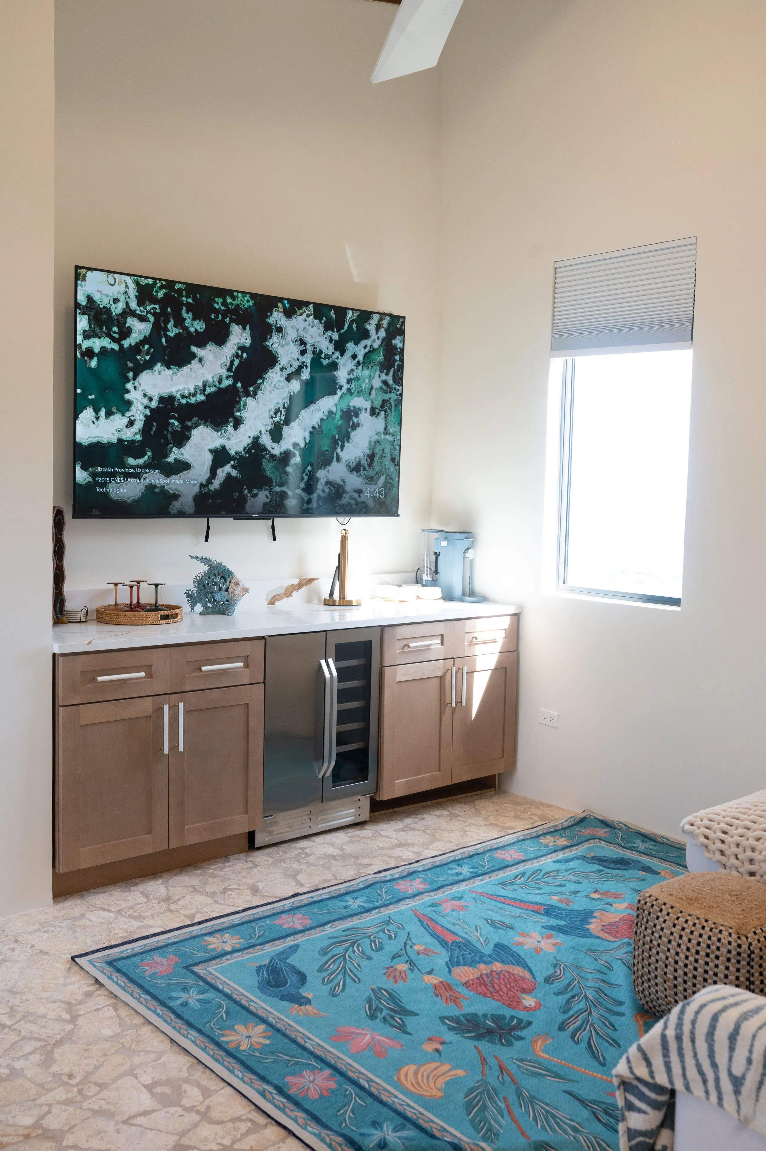 Second living area with a large television, wet bar with wine fridge and a turquoise patterned rug