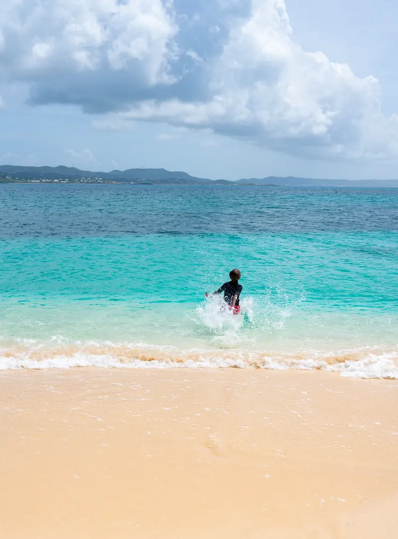 Child splashing into turquoise water off a Buck Island beach
