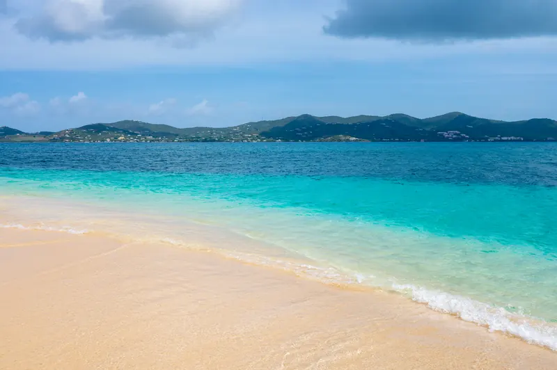 Empty sand beach and turquoise water with St. Croix hills beyond